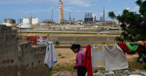 En kvinna hänger tvätt med utsikt över ett oljeraffinaderi.