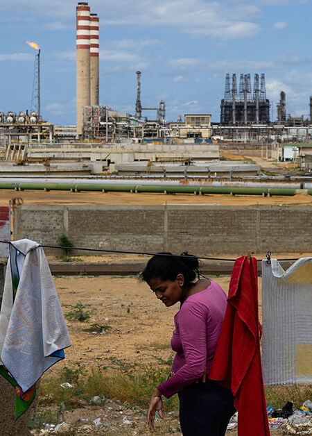 En kvinna hänger tvätt med utsikt över ett oljeraffinaderi.