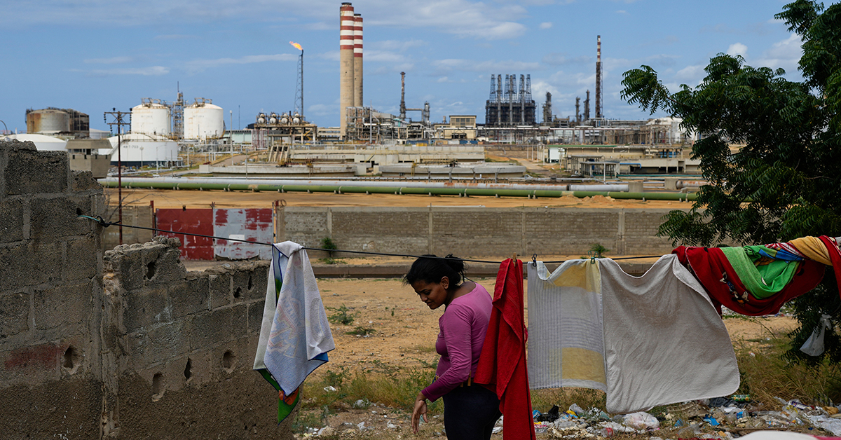 En kvinna hänger tvätt med utsikt över ett oljeraffinaderi.