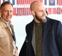 Två män i snö utanför ett hus.