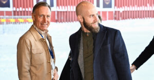 Två män i snö utanför ett hus.