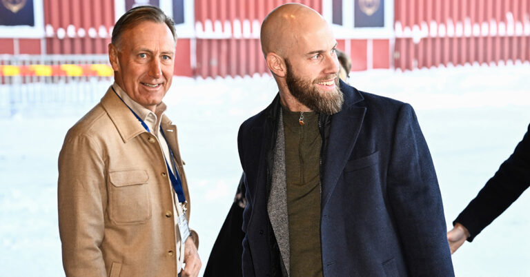 Två män i snö utanför ett hus.