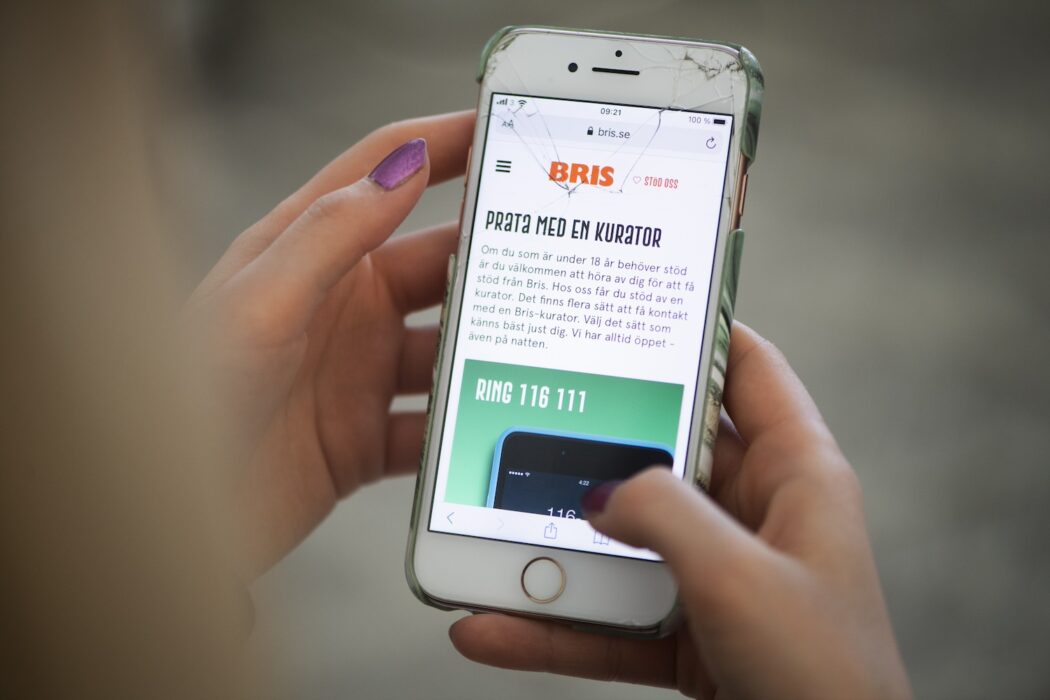 Tonåring håller mobil med Bris telefonnummer på.