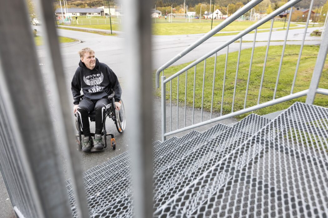 Man i rullstol nedanför en trappa som inte har en ramp.