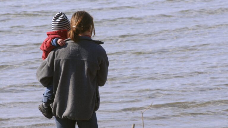 En mamma håller sitt barn i famnen.