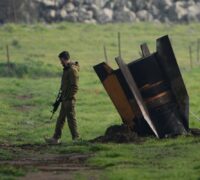 Soldat strå bredvid fragment av en oexploderad missil.