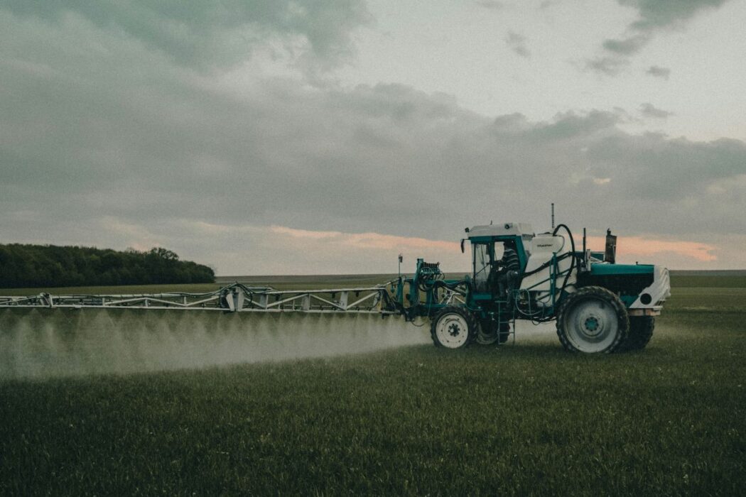 Traktor som besprutar ett fält.