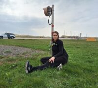 Tina Kronberg sitter fastkedjad vid en stolpe på flygplatsens landningsbaneområde.