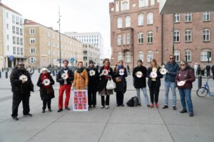 Deltagare i Matupproret står i en halvcirkel med tomma tallrikar i händerna.