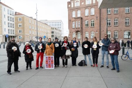 Deltagare i Matupproret står i en halvcirkel med tomma tallrikar i händerna.