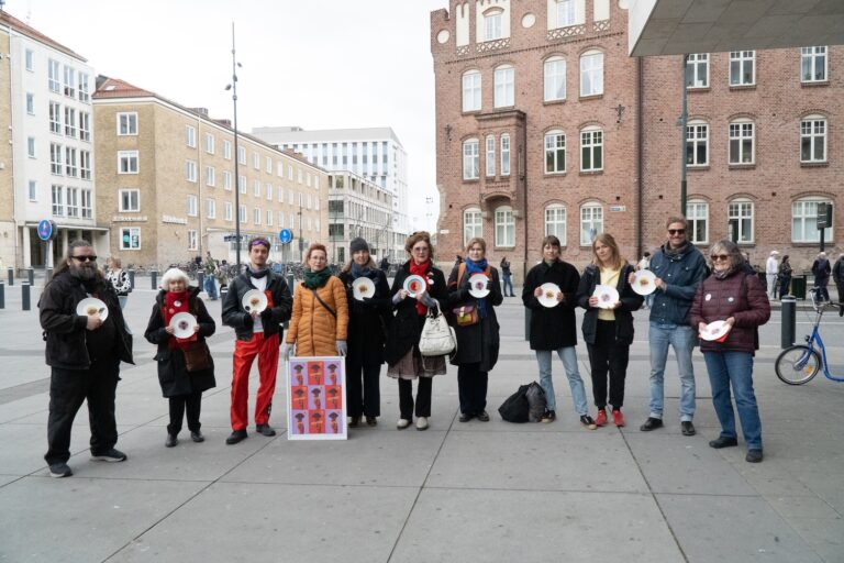 Deltagare i Matupproret står i en halvcirkel med tomma tallrikar i händerna.