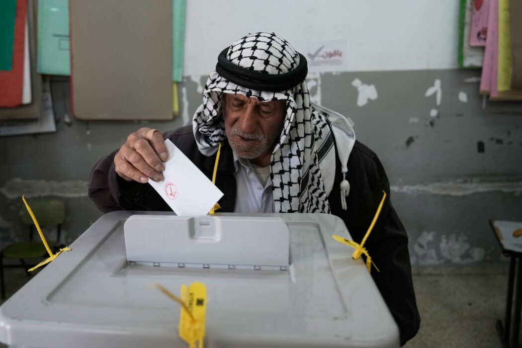 En palestinsk man lägger sin röstsedel i valurnan.
