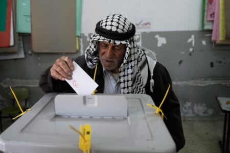 En palestinsk man lägger sin röstsedel i valurnan.