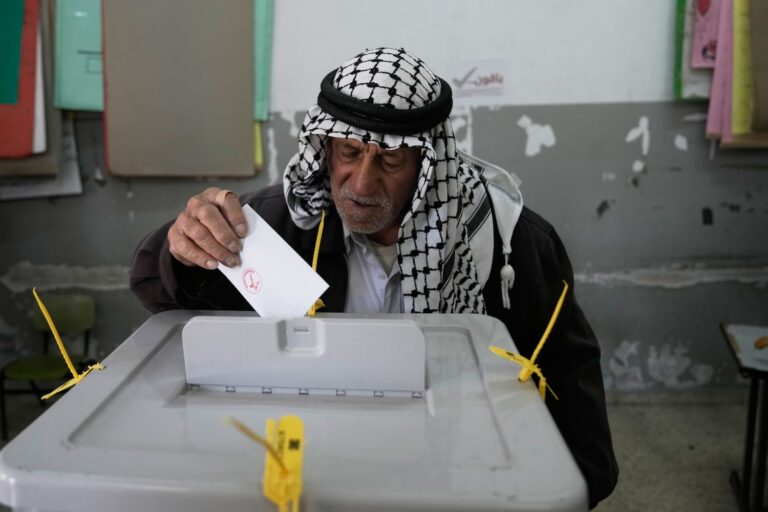 En palestinsk man lägger sin röstsedel i valurnan.