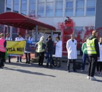 Forskare med banderoller utanför rödmålad privatjetterminal på Bromma flygplats.