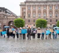Djurrättsaktivister uppradade på mynttorget med banderoller, en med ett konstgjort kycklinghuvud på sig.