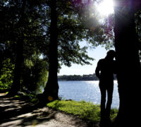kvinna står lutad mot träd vid vatten