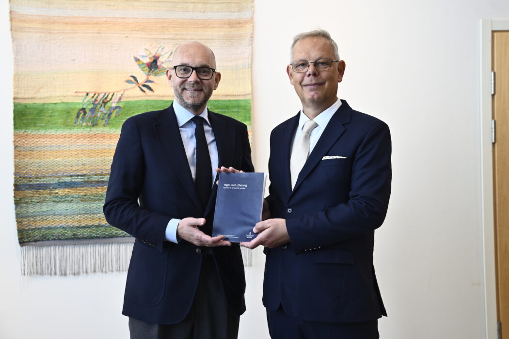 Svante Mandell, miljöekonomisk chef på Konjunkturinstitutet, överlämnar utredningen om styrmedel mot ett fossilfritt samhälle till vikarierande klimat- och miljöminister Johan Britz (L).