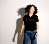 America Vera Zavala mot vit bakgrund, leende, t-shirt med ordet Attac