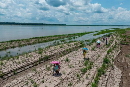 Människor går längs en del av Amazonfloden som visar tecken på torka i Santa Sofia, i utkanten av Leticia i Colombia.