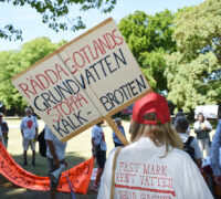 Kvinnas ryggtavla håller skylt med texten Rädda Gotlands vatten - stoppa kalkbrotten