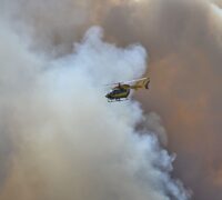 Helikopter i skyn omgärdad av mörka brandmoln.