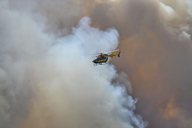 Helikopter i skyn omgärdad av mörka brandmoln.