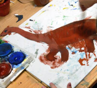 Ett barn målar en dinosaurie. Inklippt bild av skribenten.