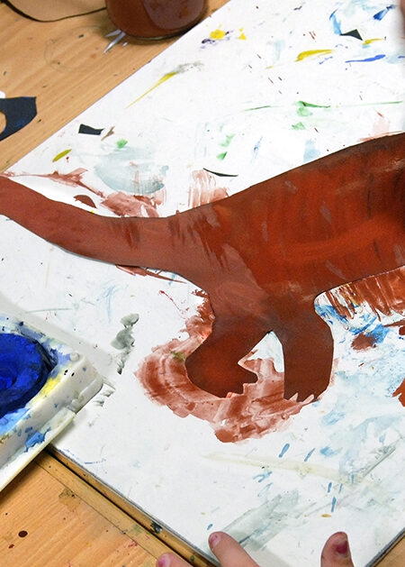 Ett barn målar en dinosaurie. Inklippt bild av skribenten.