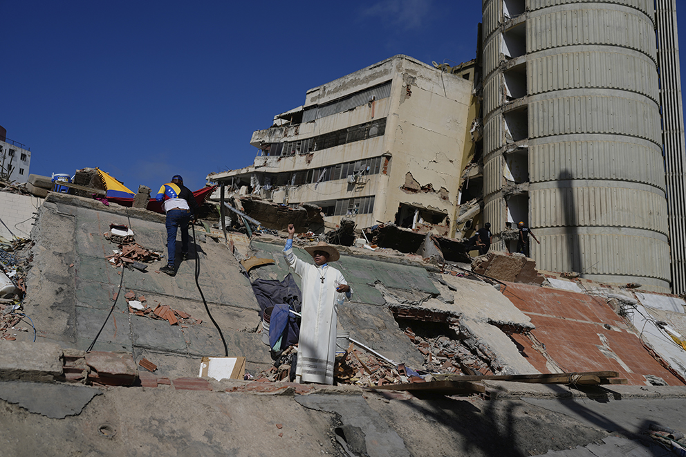En katolsk präst står bland rasmassorna efter de kraftiga jordbävningarna i La Guaira, Venezuela.
