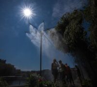 Människor svalkar sig under dimspridare i Paris under en värmebölja, lördagen den 11 juli 2026.
