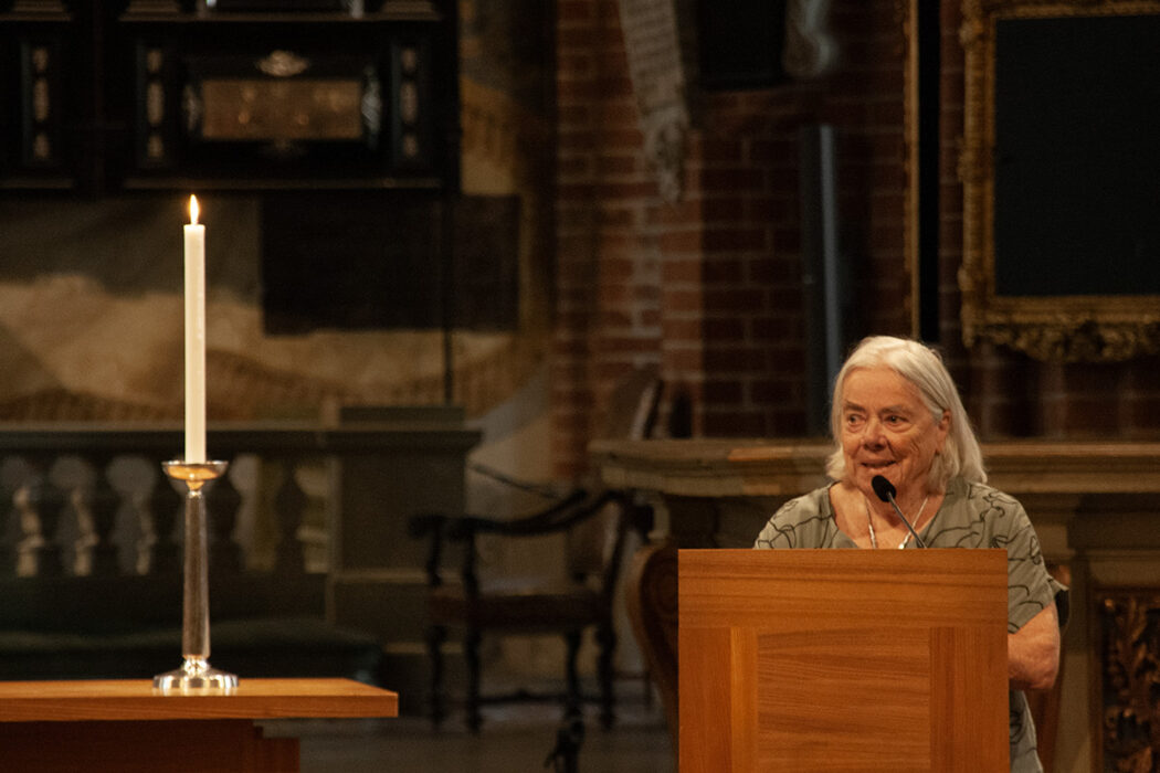 Ingela Mårtensson talar i Storkyrkan, ett levande i ljus i förgrunden till vänster