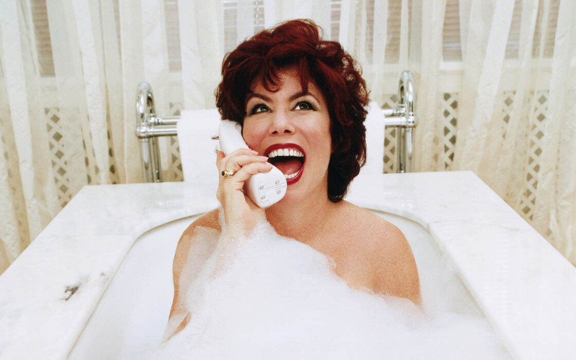 Ruby Wax talar i en stor vit telefonlur i badet