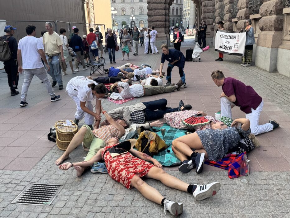 Aktivister spelar sjuka eller döda på marken, medan sjukvårdspersonal tittar till dem.