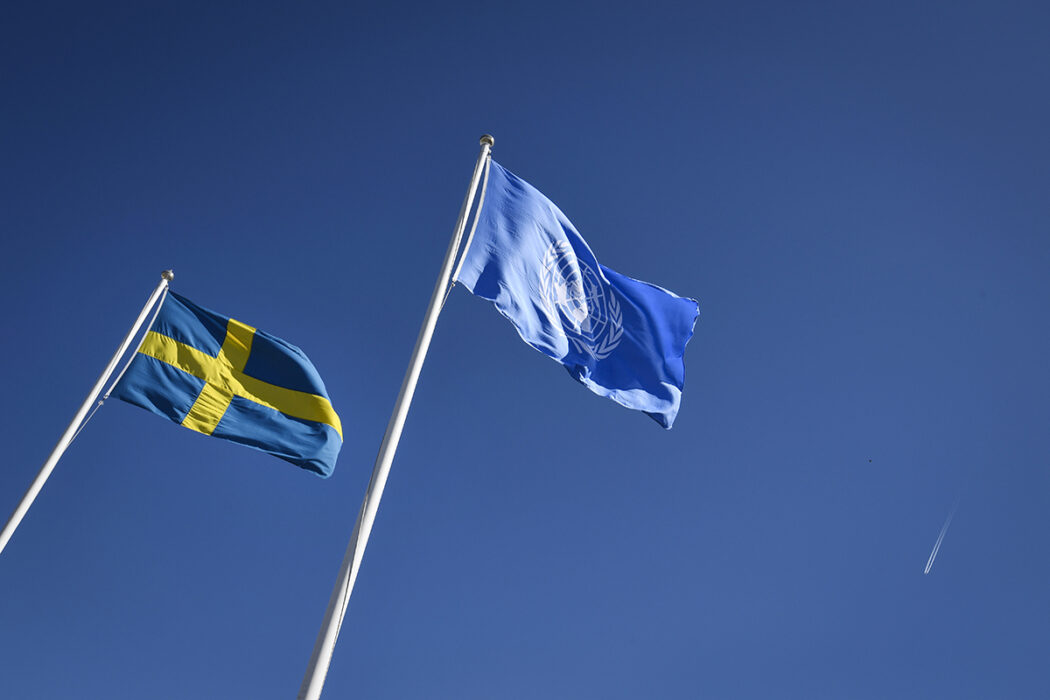 Sveriges flagga vajar intill FN-flaggam