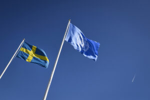 Sveriges flagga vajar intill FN-flaggam