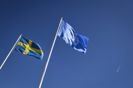 Sveriges flagga vajar intill FN-flaggam