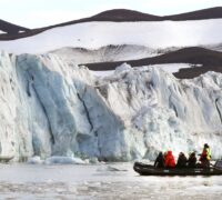 Glaciär på Svalbard där turister syns i en liten båt.