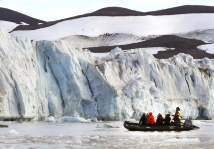 Glaciär på Svalbard där turister syns i en liten båt.