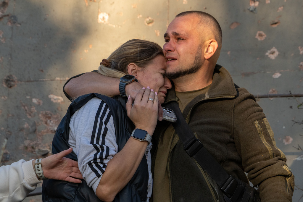 En man kramar om en kvinna efter att ha identifierat kroppen efter sin mormor, som dödades i ett ryskt flyganfall mot ett bostadsområde i Charkiv i Ukraina, fredagen den 2 oktober 2026.