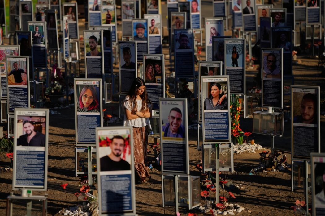 En kvinna går bland uppställda foton av personer som dödades i Hamas attack.